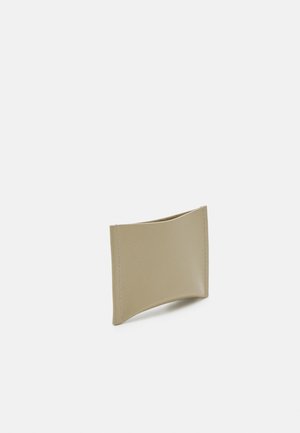 Portafoglio in pelle beige con design curvato, texture liscia, bordi cuciti e una fessura aperta per carte o contante.