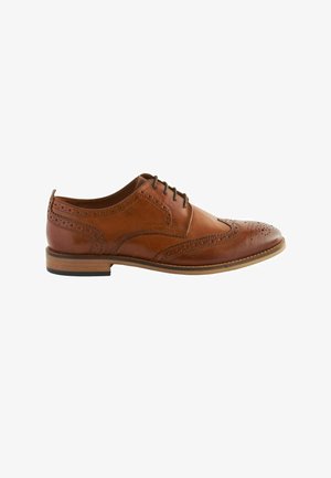 Men's brown leather brogue Oxford shoe with wingtip perforations and black laces, wooden sole, and low heel.