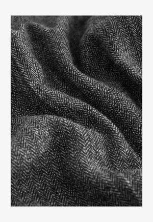 Tessuto intrecciato con motivo a spina di pesce in bianco e nero, dalla texture morbida e aspetto drappeggiato, che mostra dettagli minuti nel filo e nella tessitura.