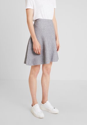 Jupe évasée grise en tissu texturé, cintrée à la taille, avec un design fluide et lisse. Portée avec des baskets blanches.