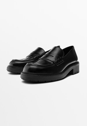 Schwarze Leder-Loafers mit einem schlanken Design, einer niedrigen, robusten Sohle und glatter Textur sowie dekorativen Nähten vorne.