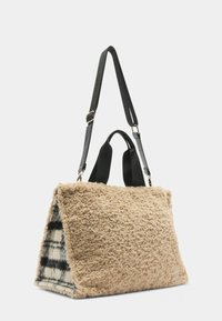 Borsa tote in pelliccia beige con un interno a motivo check bianco e nero. Presenta doppie maniglie nere e dettagli in metallo dorato.