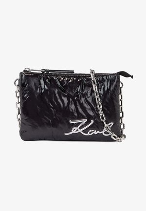 Sac à main rectangulaire noir brillant avec bandoulière chaîne argentée et logo argenté "Karl" en bas à droite sur le devant, fermeture éclair en haut.