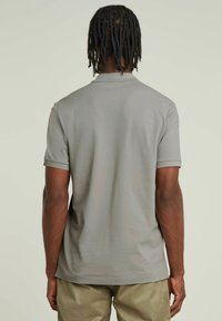 Szara, krótko rękawowa koszulka polo o miękkiej teksturze i prążkowanym kołnierzu, z prostym dołem i bez widocznych logotypów czy wzorów.