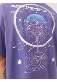Chemise violette avec un motif sur le thème de l’espace montrant un trou de ver en fil de fer, des constellations, des étoiles et le texte "ENTER THE VOID" et "CYGNUS X-1".