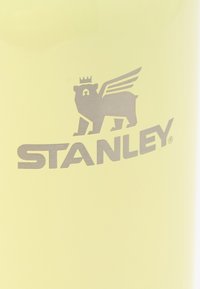 Logo d'un ours argenté ailé avec une couronne au-dessus du mot « STANLEY » sur un fond jaune clair.