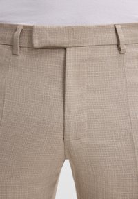 Beige strukturierte Hosen mit einem dezenten Karomuster, geradem Schnitt, seitlichen Taschen und flachem Frontdesign.