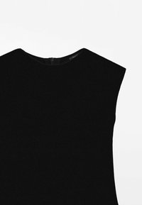 Haut noir sans manches en maille avec encolure bateau et fermeture éclair au dos, posé à plat sur un fond blanc.