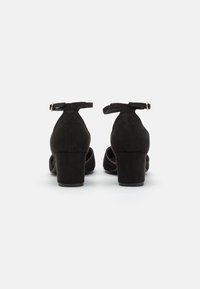 Black suede high-heeled shoes with ankle straps, rounded toes, and a block heel. Smooth texture and minimalist design; no visible patterns.