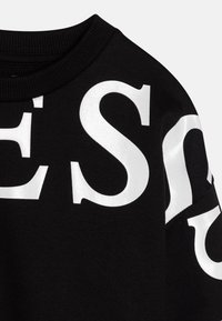 Svart sweatshirt med stor vit tryckt text på tyget. Rundad halsringning, mjuk textur och avslappnad passform.