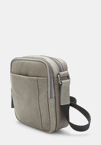 Piccola borsa a tracolla in pelle grigia con superficie testurizzata, chiusura a doppia zip e tracolla regolabile. Dotata di tasca laterale e design elegante.
