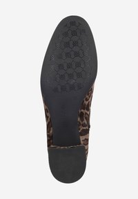 Chaussure à enfiler en imprimé léopard avec une tige en tissu texturé, une semelle en caoutchouc noir et un talon lisse, arborant un motif délimité sur la semelle.
