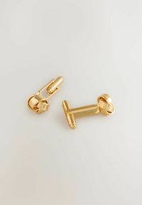 Goldene Manschettenknöpfe mit glatter, polierter Oberfläche. Einer hat ein gedrehte Design, während der andere eine rechteckige Form mit Rillenakzenten aufweist.