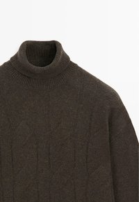 Maglione a collo alto lavorato a maglia marrone scuro con motivo a trecce, collo a coste e texture morbida. Il tessuto appare caldo e confortevole.