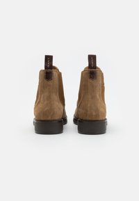 Brown suede ankle boots with elastic sides and dark brown leather accents. Features a flat sole and pull tabs for easy wear.