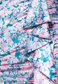 Tissu à motifs floraux en bleu et rose avec une texture satinée ; présente des volants superposés et des nuances variées de rose et de turquoise.