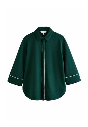 Chemise boutonnée vert foncé avec un liseré blanc le long de la ligne de boutons et des poignets de manches, dotée d'un col pointu et d'une coupe ample.
