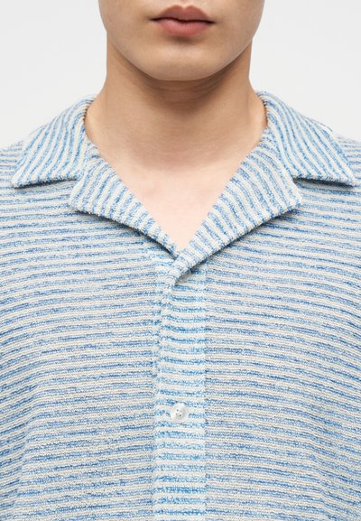 Chemise texturée à manches courtes avec des rayures horizontales bleues et blanches, dotée d'un col à revers et d'une fermeture à un bouton.
