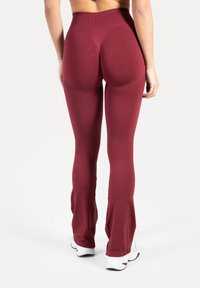 Bordowe legginsy z wysokim stanem i rozszerzanymi nogawkami, o gładkiej fakturze i rozciągliwym materiale; posiadają prążkowany pas dla wygody.