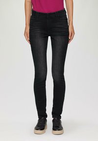 Czarne skinny jeans z denimu, z wysokim stanem, przednimi kieszeniami i subtelnymi detalami przeszycia. W zestawie z czarnymi sneakersami.