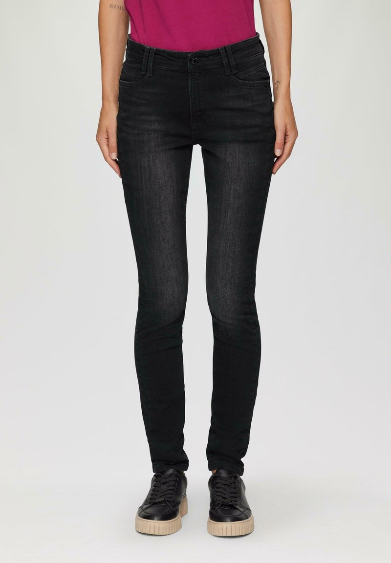 Czarne skinny jeans z denimu, z wysokim stanem, przednimi kieszeniami i subtelnymi detalami przeszycia. W zestawie z czarnymi sneakersami.