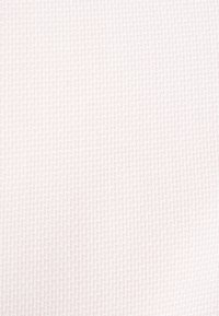 Witte textuurstof met een subtiel geweven patroon, kenmerkend door kleine in elkaar grijpende vormen, wat zorgt voor een zachte, uniforme uitstraling.