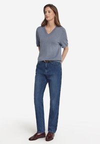 Grå kortärmad V-ringad tröja i kombination med raka blå jeans och burgundy skor, med en avslappnad passform och enkel design.