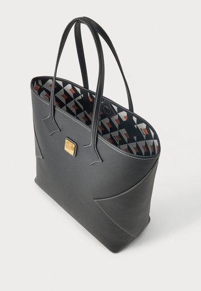 Sac cabas en cuir noir avec double poignée, surpiqûres blanches, plaque logo dorée de la marque et doublure intérieure à motif géométrique.