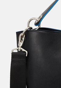 Sort lædertaske med sølvhardware, en rem med blå accenter og en tekstureret finish. Har en rund ring og klips til fastgørelse.