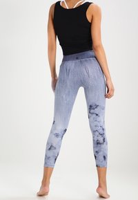 Jasnoniebieskie legginsy z teksturowanym wzorem i gładkim, szerokim pasem. Materiał wydaje się elastyczny i dopasowany, zaprojektowany do aktywności fizycznej.