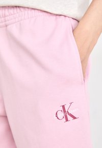 Roze katoenen joggingbroek met een elastische tailleband, zijzak en een wit logo met de tekst 'Calvin Klein' op het linkerbeen.