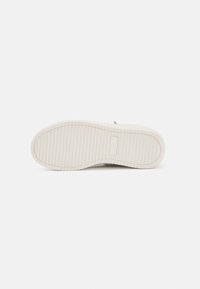 Sneaker zole, tekstūrēta balta gumija ar rievām. Apaļa forma, plakana profila un minimālistisks dizains bez redzamām rotājumiem.