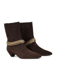 Brązowe zamszowe botki do kostki z wydłużonym noskiem, niskim obcasem i dekoracyjnym złotym paskiem z ćwiekami wokół środkowej części łydki.