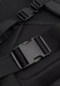 Svart nät ryggsäcksmaterial med justerbara svarta remmar och plastspänne. Texturerad yta med en ventilerande design för komfort.