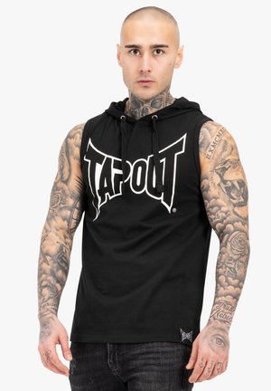 Juodas be rankovių džemperis su "TAPOUT" logotipu balta spalva, su raišteliu ir tekstūruota medžiaga. Pastebimi tatuiruotės ant rankų.