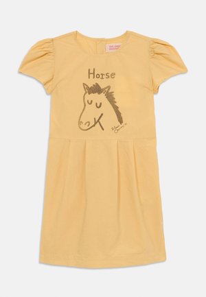 Žuta pamučna haljina s kratkim napuhanim rukavima, s grafikom konja i natpisom "Konj" u smeđoj boji, te skupljenom suknjom za puniji izgled.