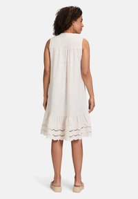 Ärmelloses Leinenkleid in Off-White mit einem ausgestellten Saum, der über Laser-Cut-Details verfügt. Gerade geschnitten, lockere Passform und weiche Textur.