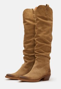 Bottines en suède marron, montant jusqu'au genou, avec un design décontracté, un bout pointu et un talon en bois de hauteur moyenne ; dotées d'un onglet en tissu pour un enfilage facile.