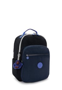 Sac à dos en tissu noir et bleu marine avec une fermeture éclair argentée, une poignée supérieure et un porte-clés en forme de singe bleu détachable. Présente une patch logo rond sur le devant.