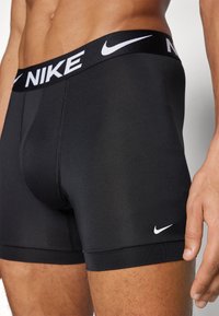 Black Nike boxer shorts feature a fitted design with a soft waistband displaying the Nike logo in white, crafted from stretchy material.