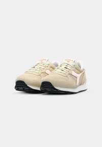Beige sneakers with a suede and mesh upper, featuring white and orange accents, a black rubber sole, and lace-up design.