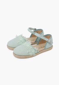Jasnoniebieskie espadryle z teksturowanego materiału, ozdobione kwiatowymi akcentami na sznurowadłach oraz z paskiem wokół kostki. Podeszwa owinięta jutą dla dodatkowego wykończenia.