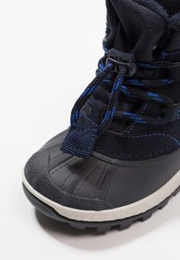 Granatowe wodoodporne buty z teksturowanym gumowym noskiem, regulowanymi sznurowadłami i solidną podeszwą. Wyposażone w ocieplinę z polaru i trwałe materiały wierzchnie.