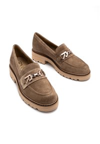 Bruine suede instappers met een lage, gestructureerde rubberen zool. Voorzien van een decoratieve zilveren ketting en stikseldetails, met een ronde neus.