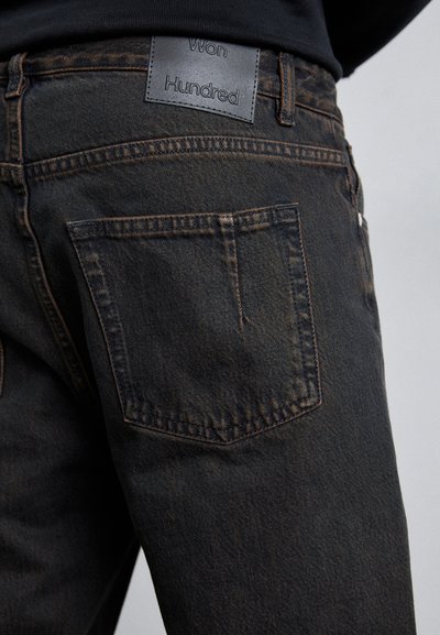 Mustad mustreid teksad omavad tagataskut klapiga ning halli nahkpõhja, millel on silt "Won Hundred". Materjal on pehme ja kerge tuhmumisega.