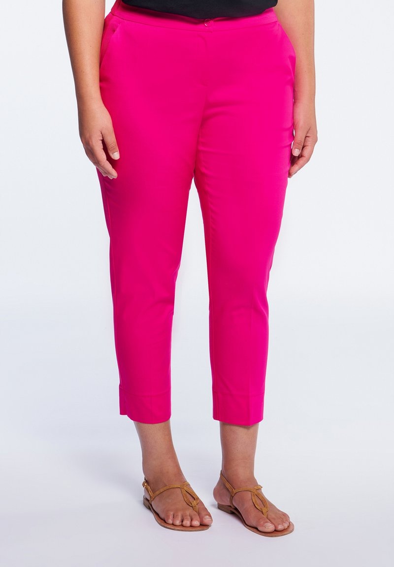 Skräddarsydda, korta byxor i ljusrosa tyg med en slät yta och sidofickor, tillsammans med ljusbruna sandaler.