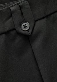 Czarna tkanina o gładkiej fakturze z zapięciem na guzik w pasie, obok projektu z płaskim złożeniem.