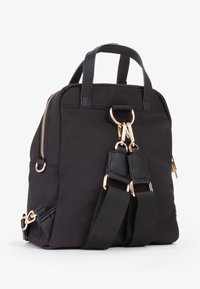 Zaino nero in nylon con dettagli in faux pelle, hardware oro, doppio manico superiore e spallacci regolabili; presenta una chiusura con zip e tasche laterali.