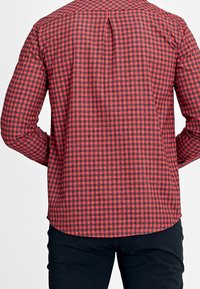 Rood en zwart geruit shirt, geweven stof, lange mouwen, plooi detail aan de achterkant, afgeronde zoom, gecombineerd met donkere broek.