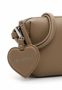Brown leather handbag with a textured finish, featuring a zipper closure, a short strap, and a heart-shaped tag inscribed with "EMILY&NOAH."